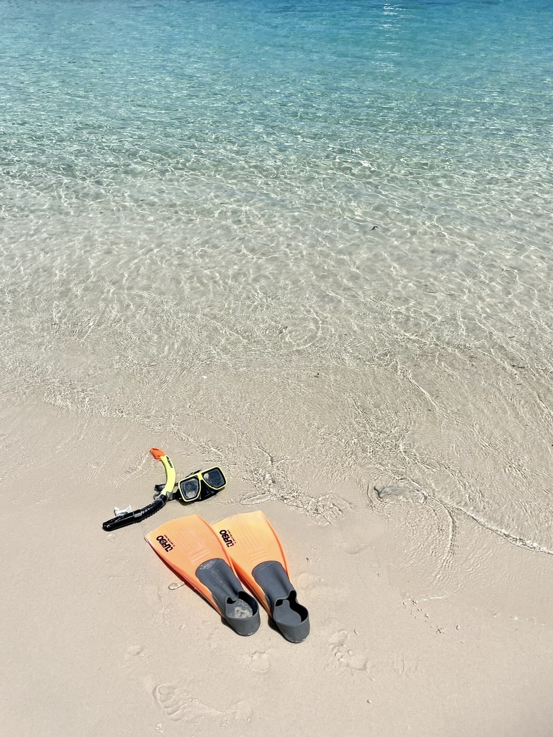 Snorkel and fins on clear shallow water